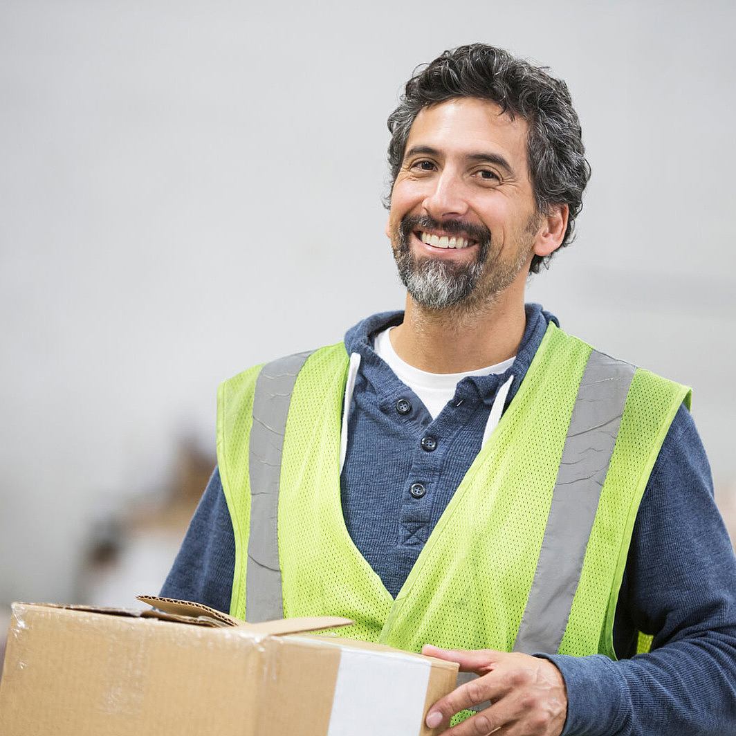 Lagerhelfer trägt Karton in einer Lagerhalle.