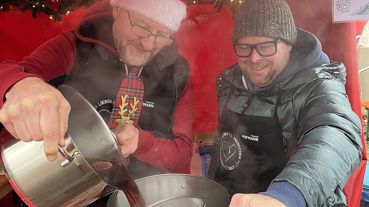 Zwei Mitarbeiter kochen am Stand von Hofmann Personal beim Weihnachtsmarkt Langwasser.