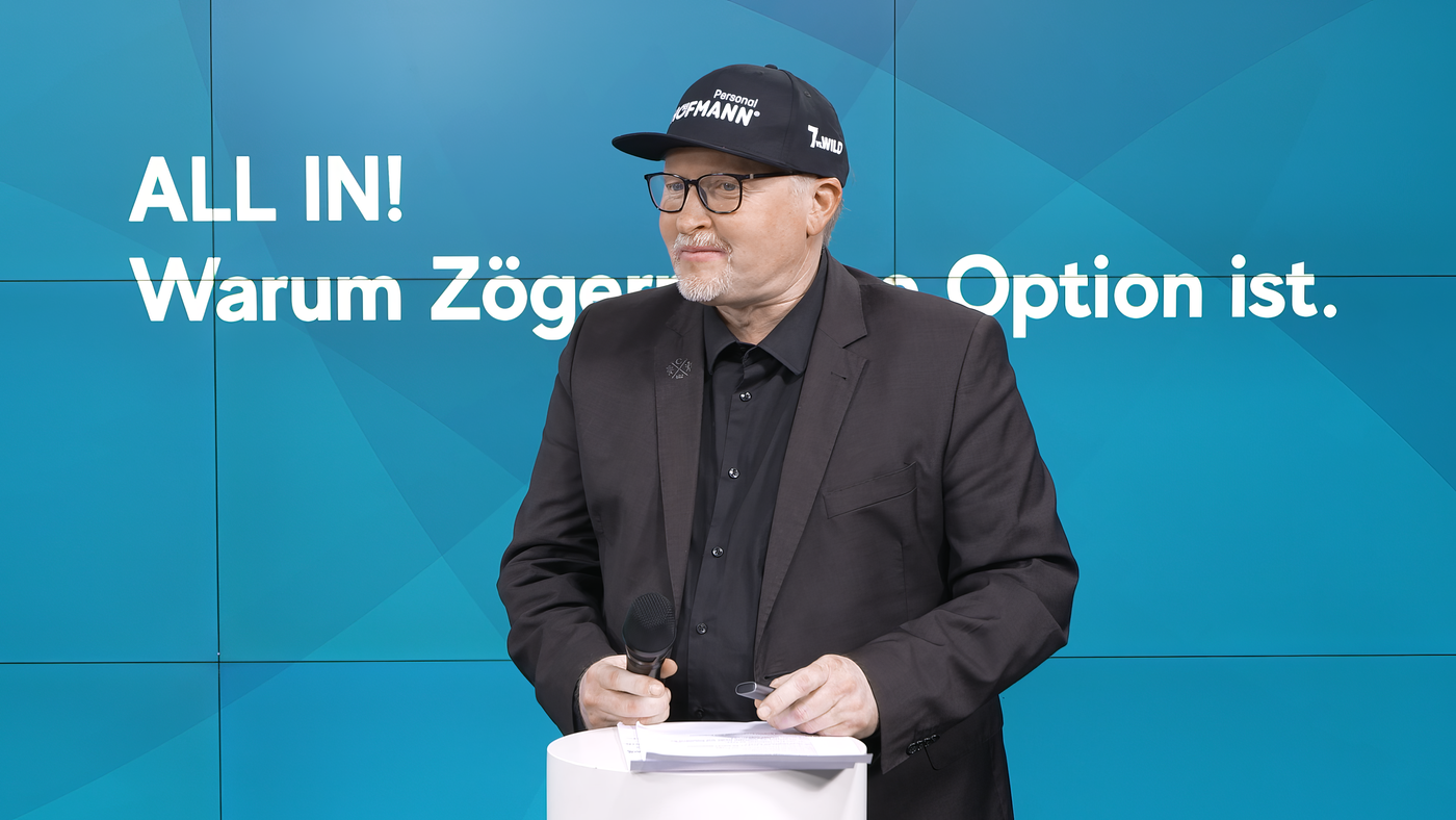 Joey Kelly als Redner bei einem Streaming-Event von Hofmann Personal vor blauem Hintergrund.