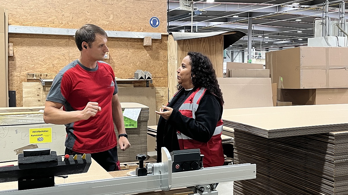 Mitarbeiter im Gespräch mit einer Hofmann-Personalbetreuerin in der Produktionshalle des Verpackungsherstellers
