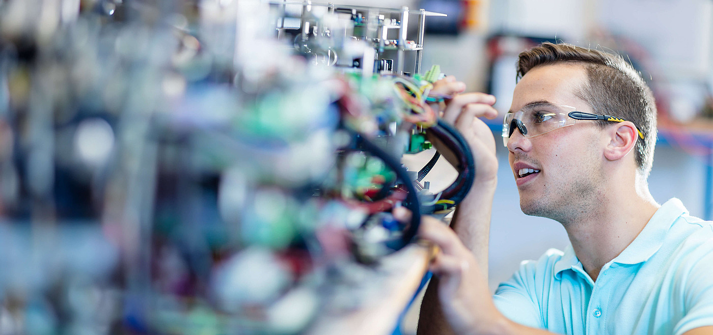 Ein Elektroniker arbeitet konzentriert an einer komplexen elektrischen Schaltanlage