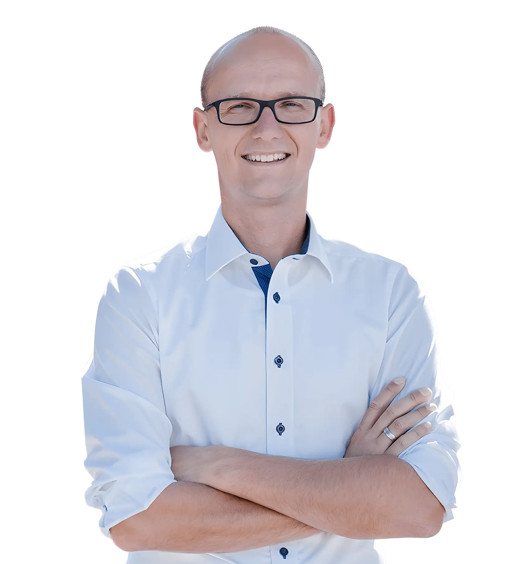 Ein lächelnder, glatzköpfiger Mann mit Brille und hellblauem Hemd steht mit verschränkten Armen