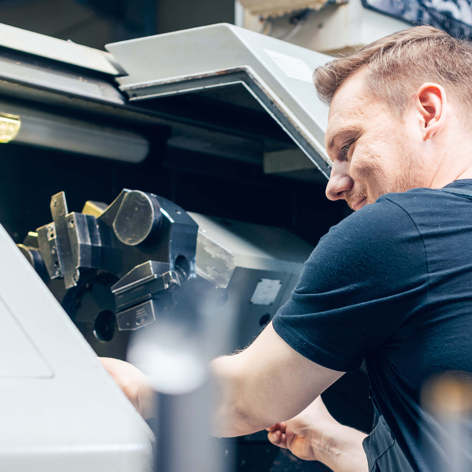 Helfer arbeitet an CNC-Maschine und repräsentiert den Einsatz im gewerblich-technischen Bereich in der Zeitarbeit.