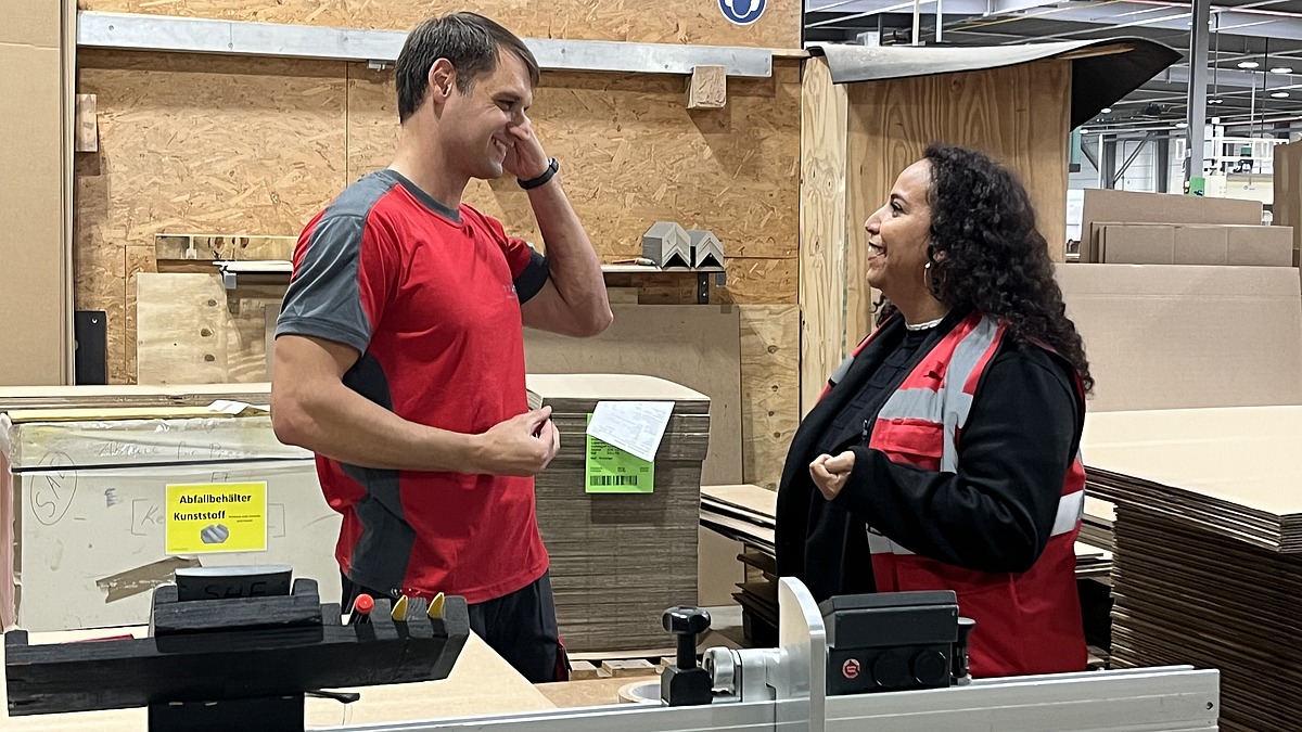 Mitarbeiter im Gespräch mit einer Hofmann-Personalbetreuerin in der Produktionshalle des Verpackungsherstellers