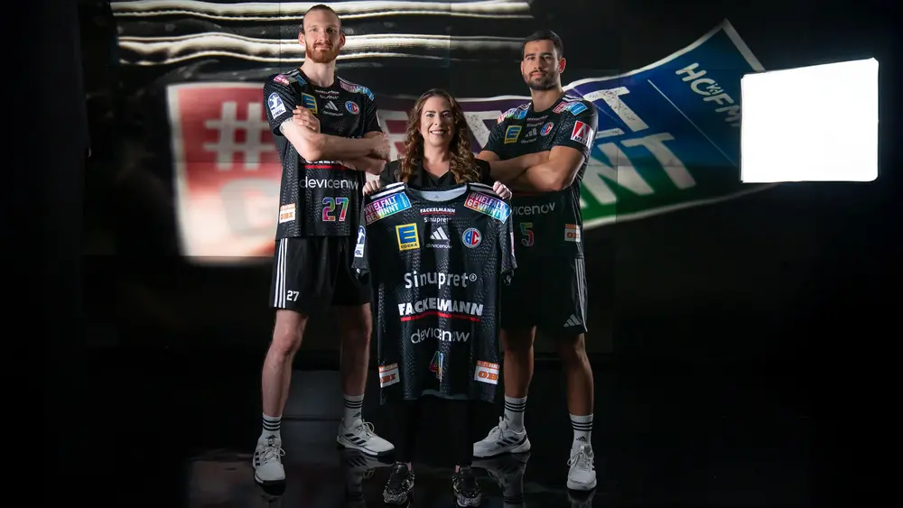 Sonja Heinrich von Hofmann Personal präsentiert mit zwei Handballspielern das HC-Erlangen-Sondertrikot der Vielfalt gewinnt Tour 2026.
