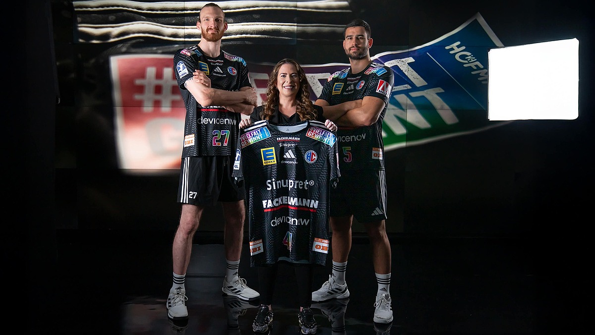 Sonja Heinrich von Hofmann Personal präsentiert mit zwei Handballspielern das HC-Erlangen-Sondertrikot der Vielfalt gewinnt Tour 2026.