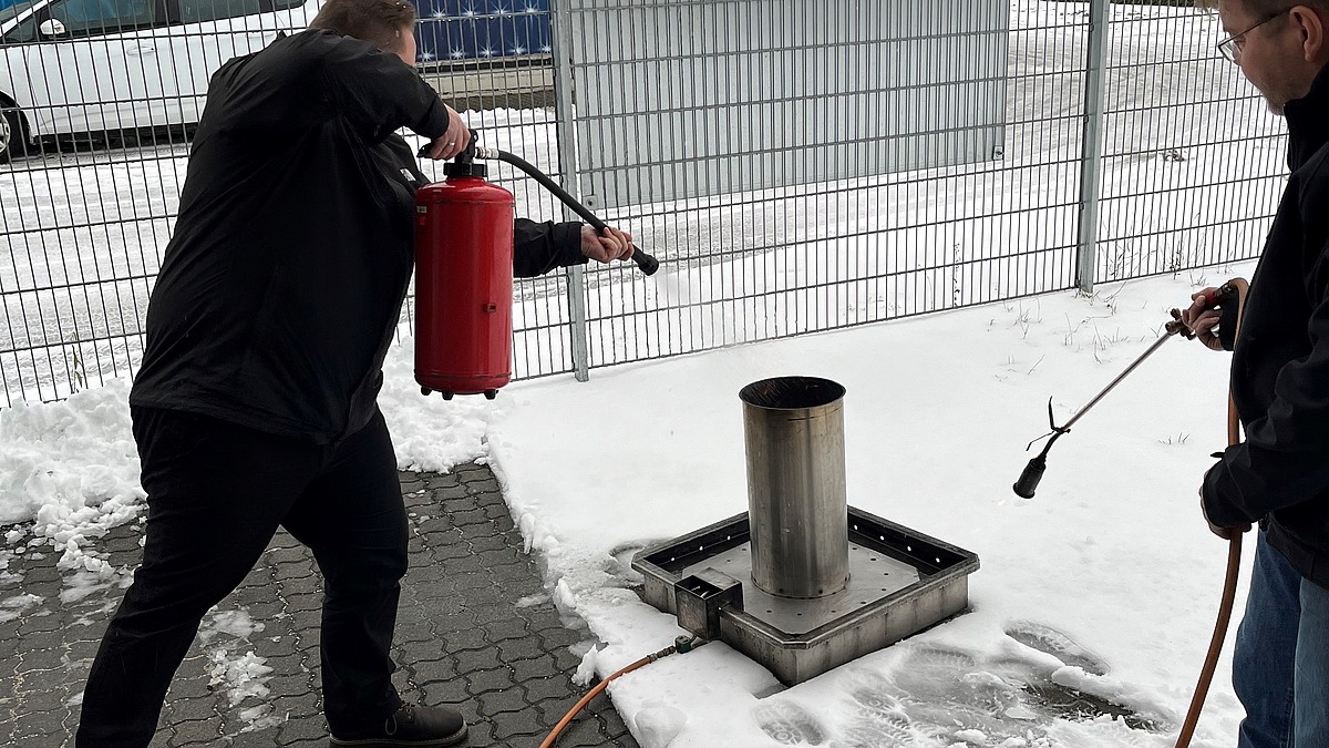 Mitarbeiter von Hofmann Personal löscht bei einer Brandschutzhelferschulung ein kleines Feuer.