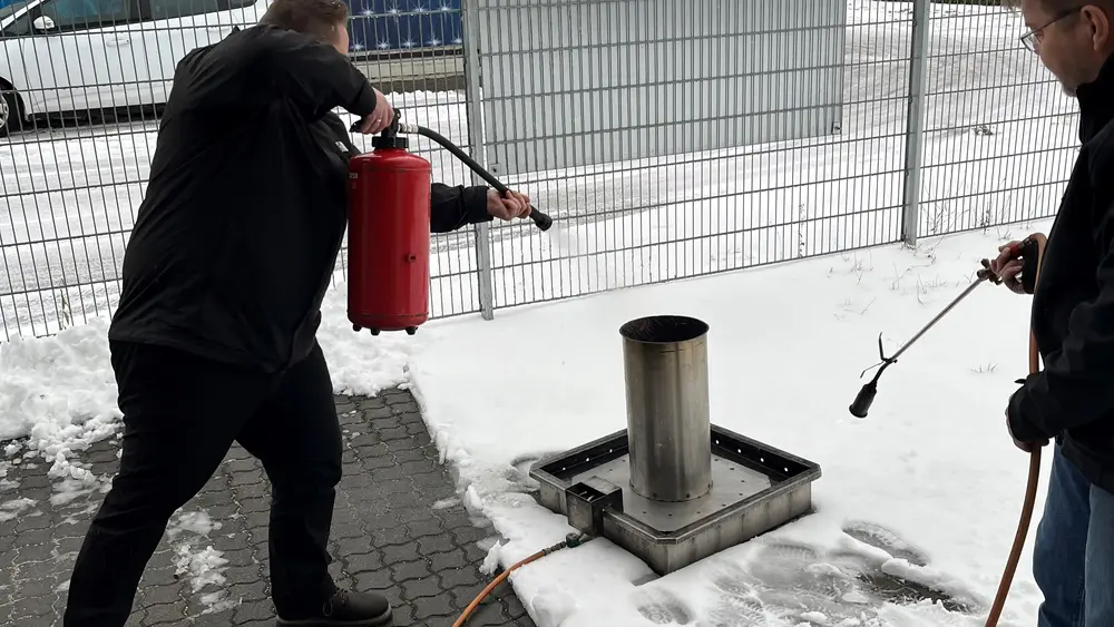 Mitarbeiter von Hofmann Personal löscht bei einer Brandschutzhelferschulung ein kleines Feuer.