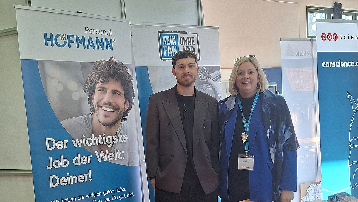 Zwei Mitarbeiter stehen vor dem Messestand von Hofmann Personal beim Tag der Technik 2026 in Erlangen.