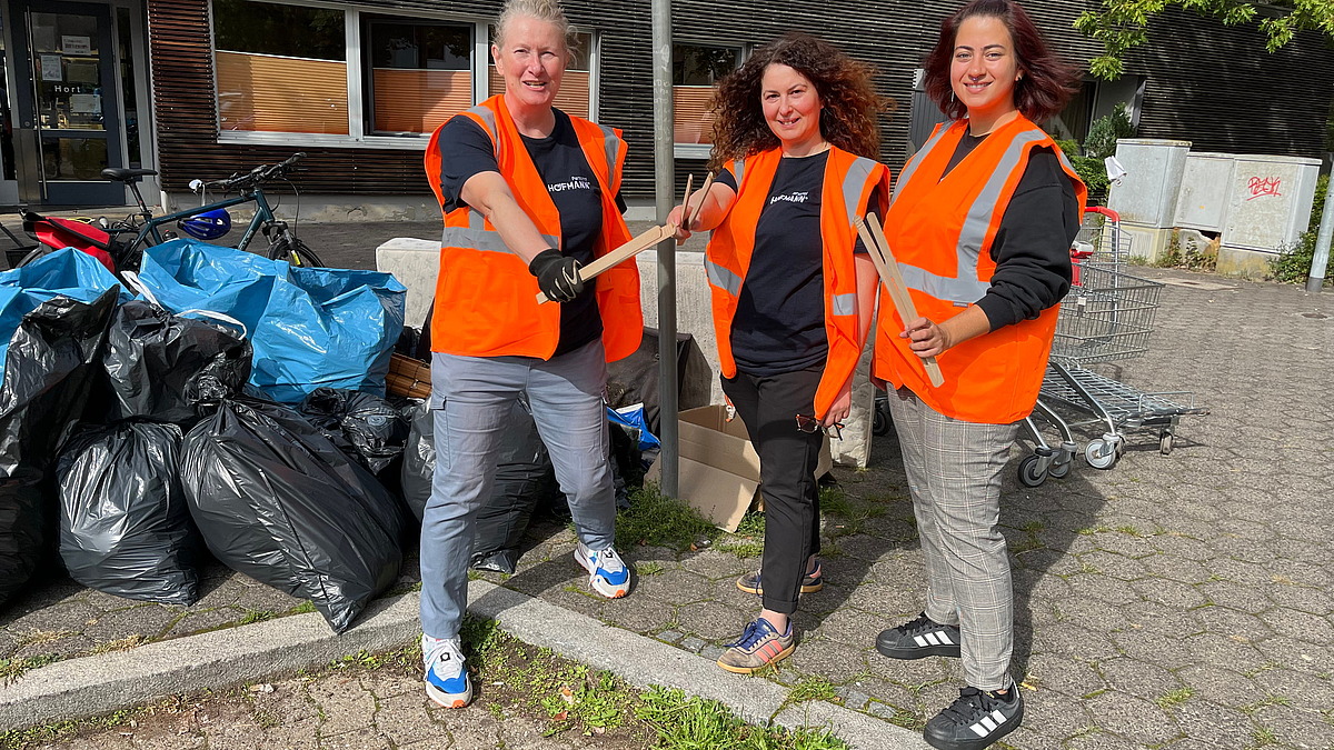 Drei lächelnde Mitarbeiter von Hofmann Personal, die beim World Cleanup Day in Langwasser tatkräftig geholfen haben.
