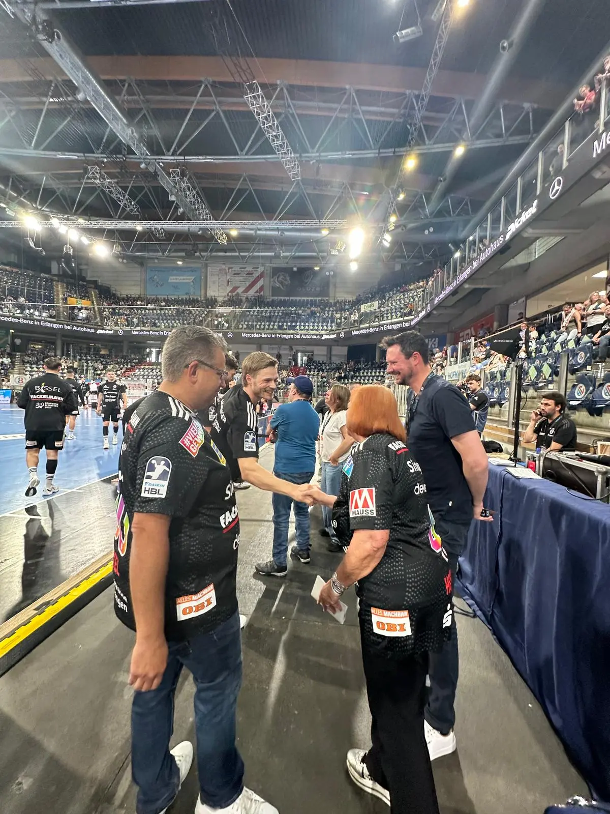 Handball-Schiedsrichter in schwarzen Trikots in der Arena – Vielfalt gewinnt Tour Hofmann Personal