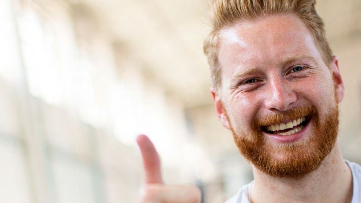 Lächelnder Mitarbeiter von Hofmann Personal zeigt den Daumen nach oben.