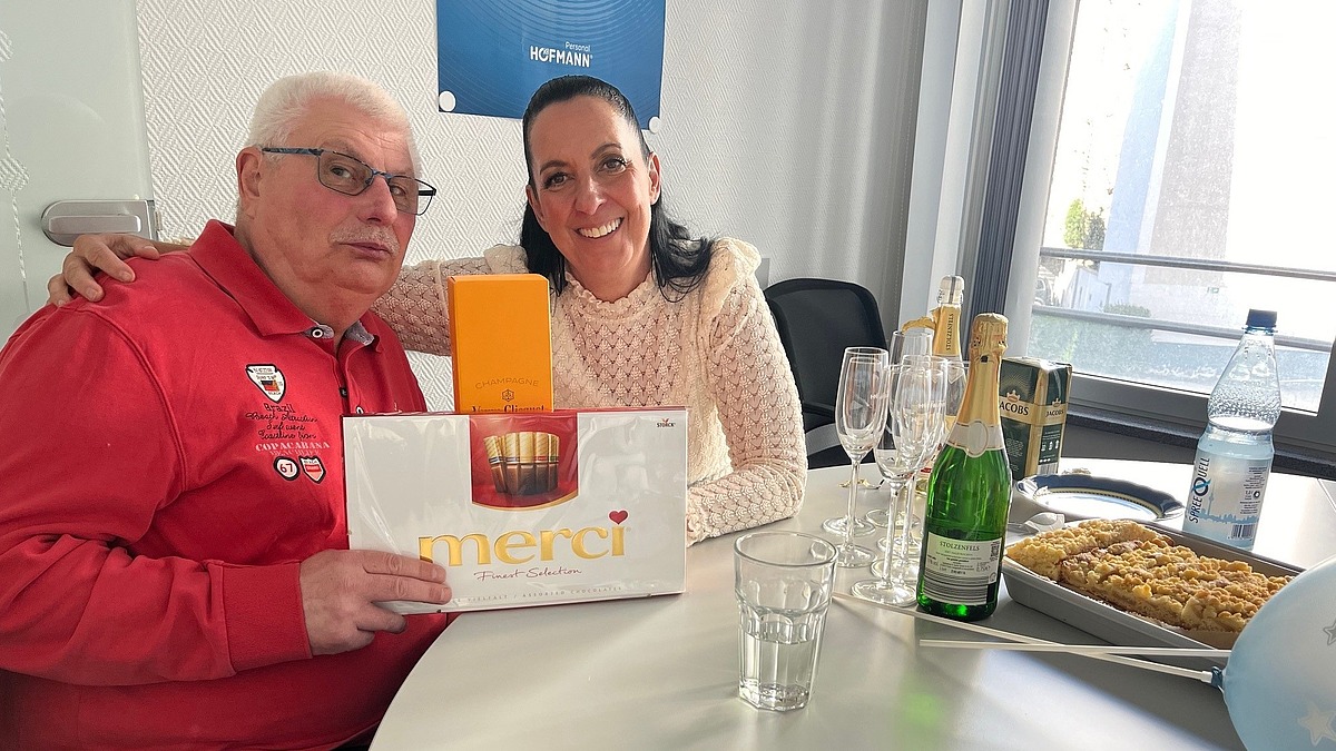 Einem Mitarbeiter wird zum Ruhestand ein Geschenk überreicht, symbolisch für Zusammenhalt und Teamgeist bei Hofmann Personal.