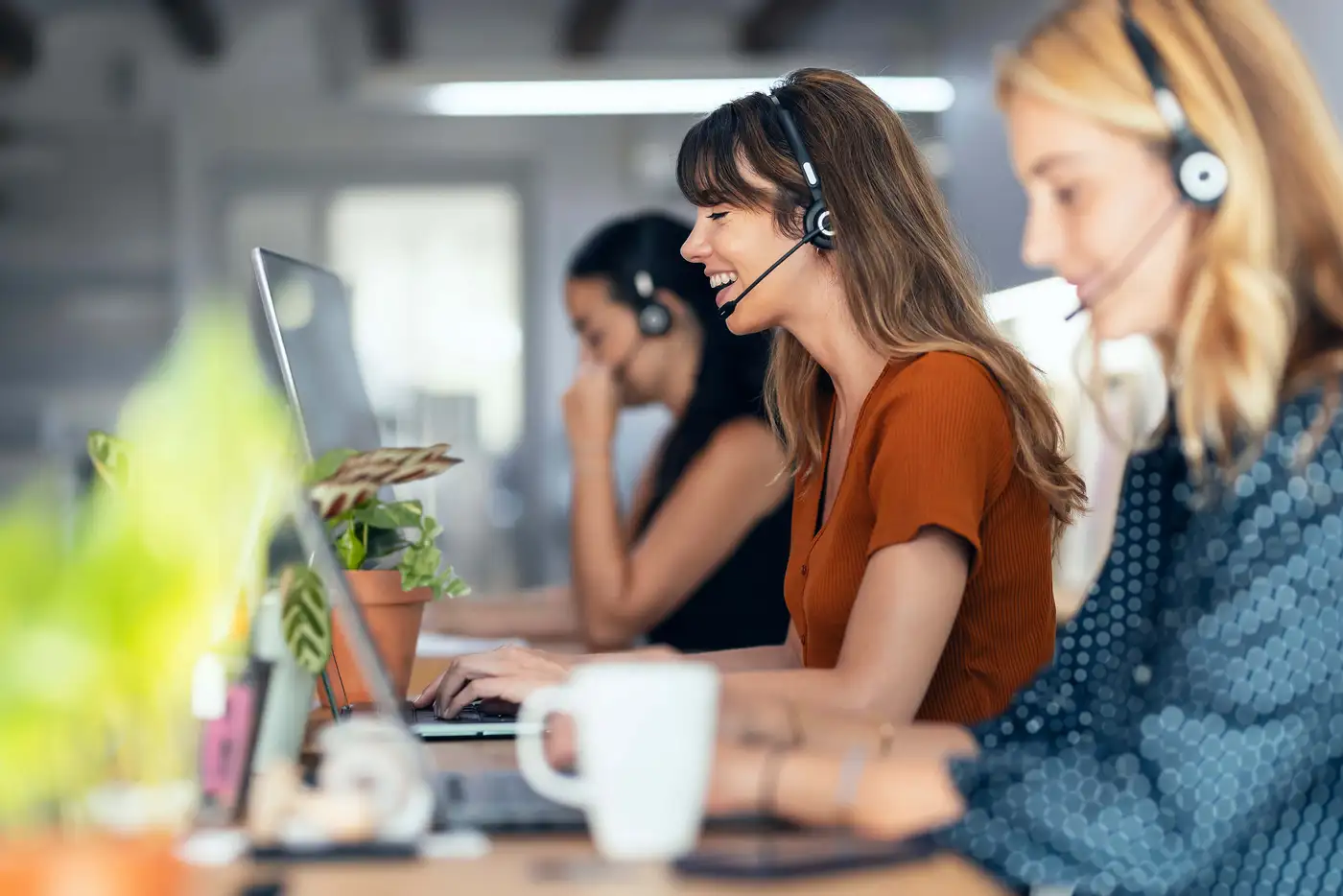Call Center Agents mit Headsets arbeiten konzentriert an Computern in einem modernen Büro